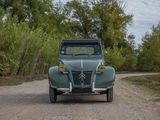 a green car that is driving down a dirt road