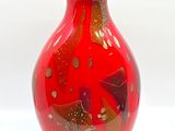 un vase rouge surmonté d'un couvercle jaune, posé sur une surface blanche