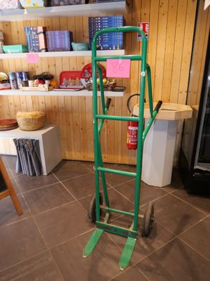 a green hand truck with a green handle in a room
