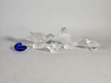 plusieurs oiseaux en verre posés sur une table, à côté d'un œuf bleu