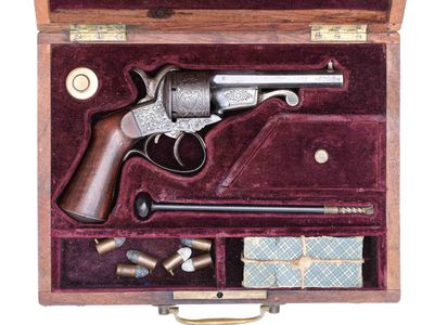 un vieux pistolet dans un coffret en bois contenant d'autres objets