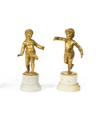 two gold statues of a boy and a girl on marble bases