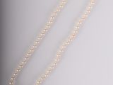 un collier de perles blanches avec un fermoir en or sur fond blanc