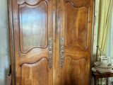 une armoire en bois dans une pièce où se trouvent une table et des chaises