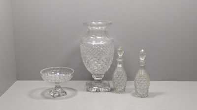 une table blanche sur laquelle se trouvent un vase, un verre et un verre à vin