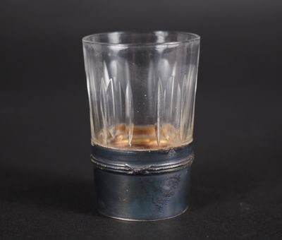 un verre à shot contenant un liquide, posé sur une surface noire