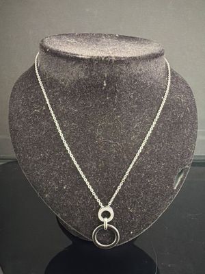collier en argent avec un pendentif en forme de cercle, présenté sur un socle en forme de mannequin