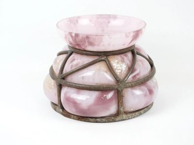 un vase rose muni d'un support métallique sur fond blanc