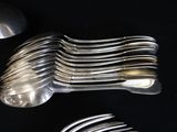 a lot of silver spoons and forks on a black table