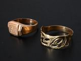 two gold rings with a signet on them sitting on a black surface
