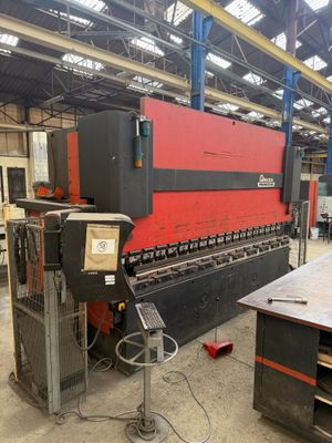 a red and black machine in a warehouse with a large machine in the background