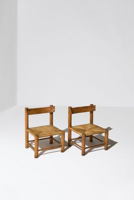 deux chaises en bois assises l'une à côté de l'autre sur une surface blanche