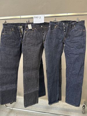 trois paires de jeans suspendues à un portant dans un magasin