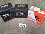 trois boîtes de piles Nitro posées par terre à côté d'une boîte de piles Nitro