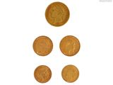 quatre types différents de pièces d'or sont présentés sur une surface blanche