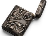 an antique silver cigarette case with a flower design on it