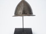 an antique helmet on a stand on a white background