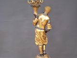 a gold statue of a man holding a candelabra
