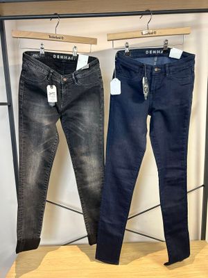 deux paires de jeans suspendues à un portant dans un magasin de vêtements
