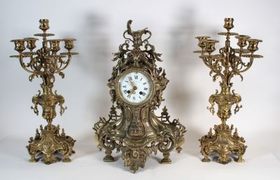 Trois horloges anciennes sont posées les unes à côté des autres sur une surface blanche