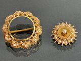 two gold brooches with pearls on them sitting on a table