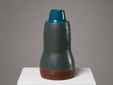 un vase bleu posé sur un socle blanc