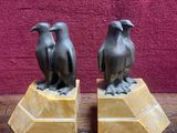 une paire d'oiseaux en bronze posés sur des socles en marbre, posés sur une table en bois