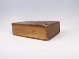 an old book sitting on top of a white surface with a white background