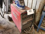 une soudeuse dans le garage, avec un casque posé dessus