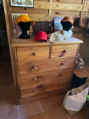 une commode en bois sur laquelle sont posés trois chapeaux