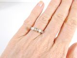 a woman ' s hand with a pearl ring on it