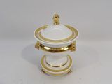 a white and gold covered dish on a white table