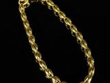 a gold chain bracelet on a black background