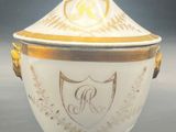 an image of a white and gold covered bowl with a crest on it