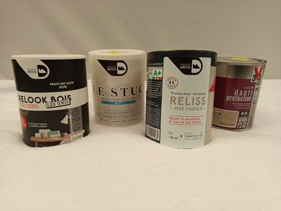 Plusieurs pots de peinture sont alignés sur une surface blanche