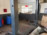 une photo d'un garage avec un grand pont élévateur au milieu de la pièce