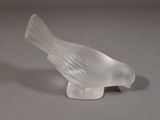 un petit oiseau en verre posé sur une table
