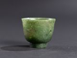 une petite tasse verte posée sur une surface noire