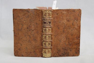 un vieux livre à la couverture marron et à la reliure dorée