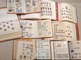 plusieurs livres ouverts, sur lesquels sont apposés des timbres, posés sur une table
