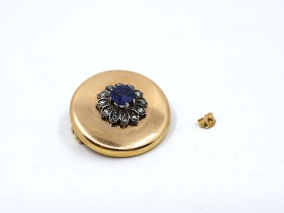a close up of a gold button with a blue flower on it