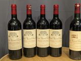 six bottles of wine are lined up on a wooden tray