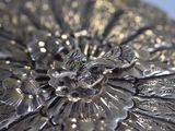 a close up of a silver plate with a flower on it