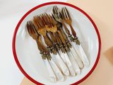 several forks and spoons are in a bowl on a table