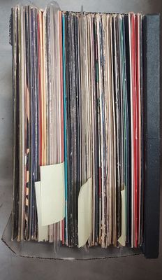 beaucoup de disques vinyles dans une boîte posée sur la table