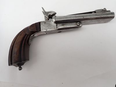 un vieux pistolet avec une poignée en bois sur une surface blanche