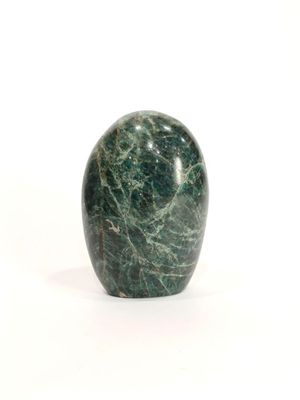 une pomme en marbre vert posée sur une surface blanche, sur fond blanc