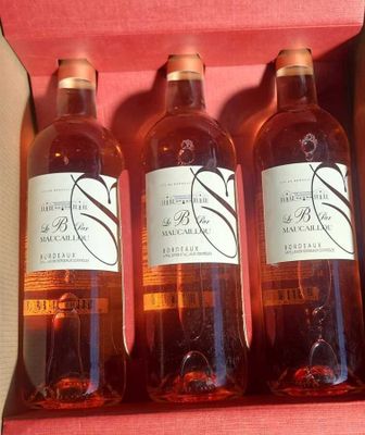 three bottles of wine are in a pink box on a table