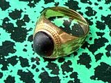 a gold ring with a black stone in it on a green surface