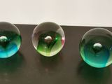 three glass marbles sitting on top of a table next to each other